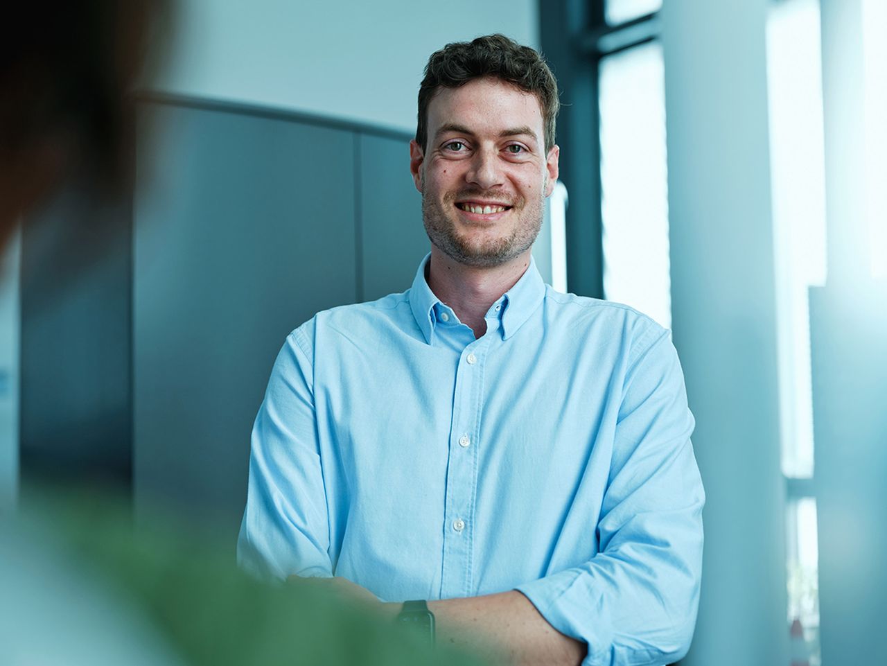 A portrait of Mario, who stands smiling with arms crossed in Octapharma office.
