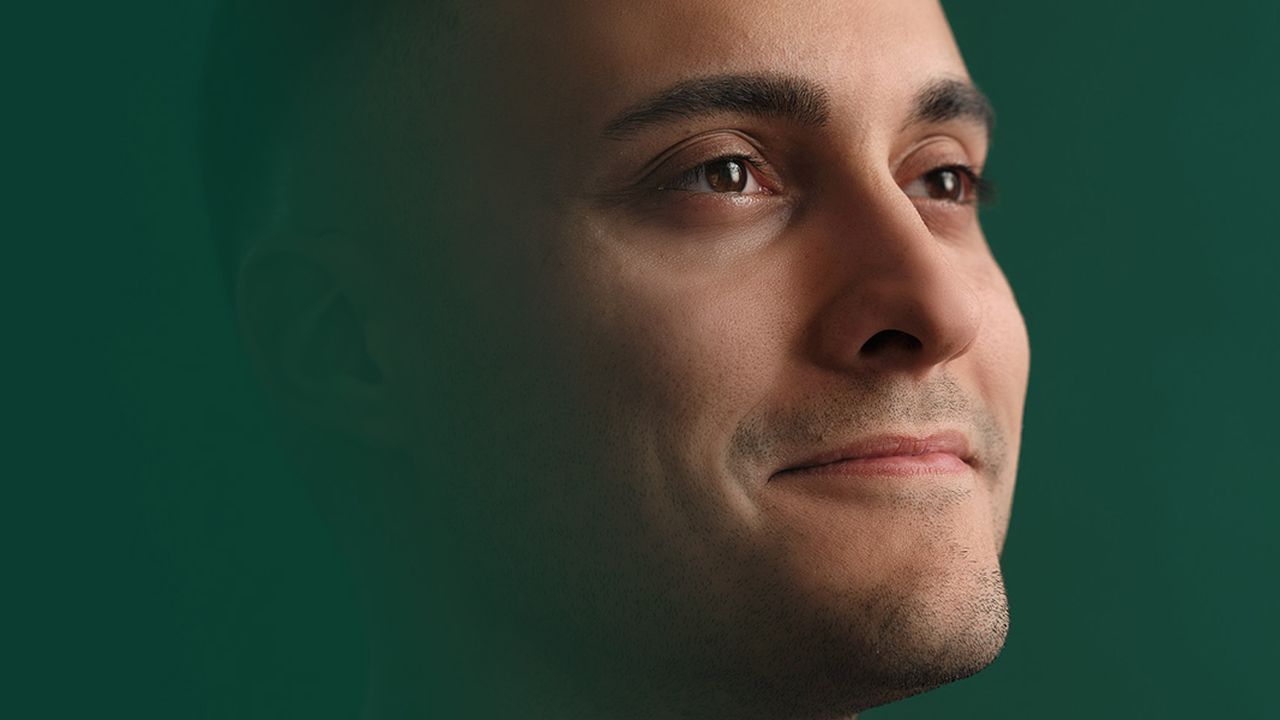 A man gazes upward with a slight smile, set against a dark green background.