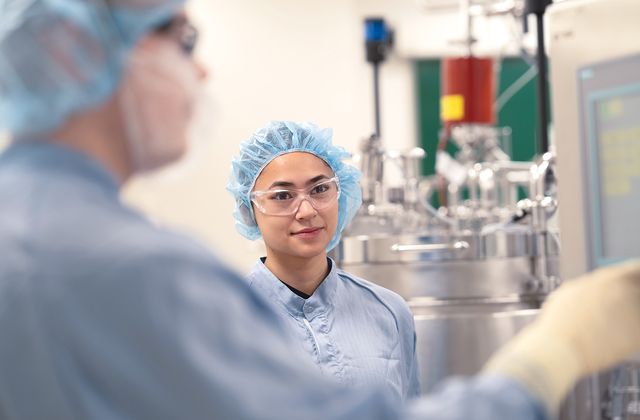 Octapharma employee in protective clothing and safety glasses working inside a pharmaceutical production facility.