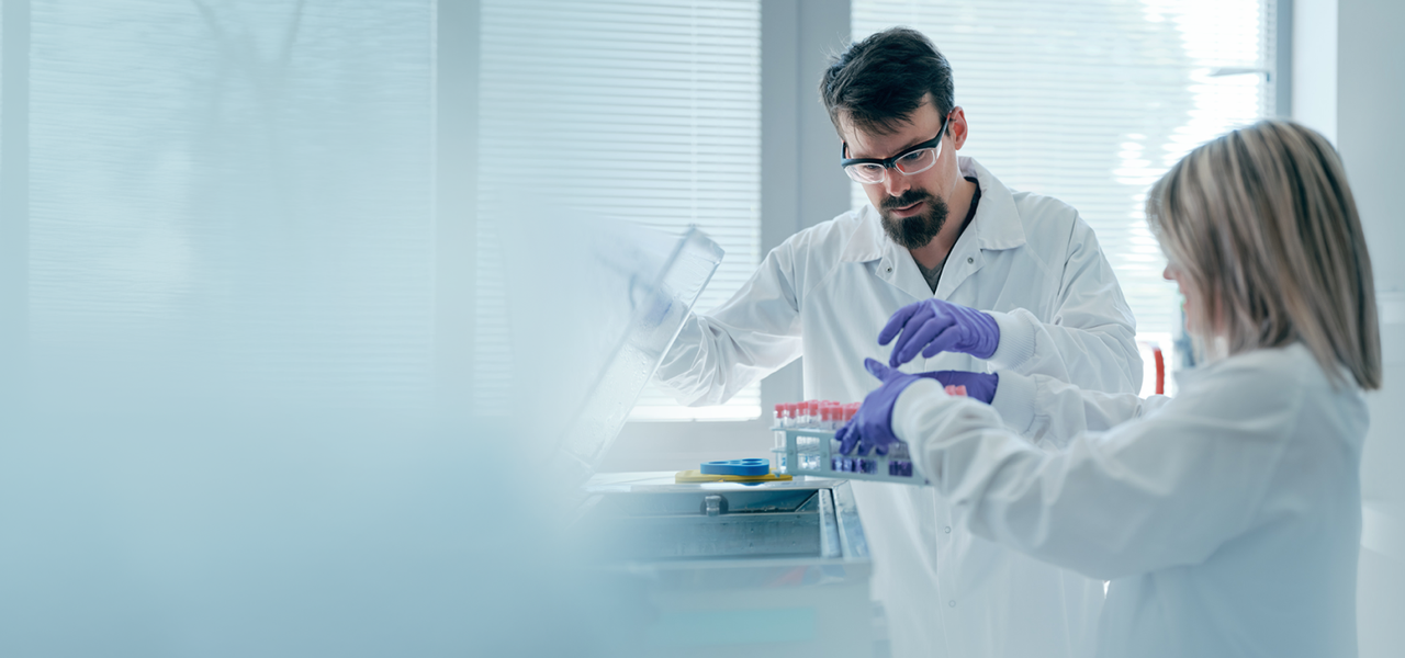 Two scientists in lab coats working with test tubes in a laboratory.