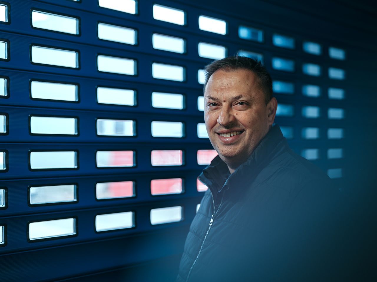 Man smiling into the camera standing in front of a roller shutter