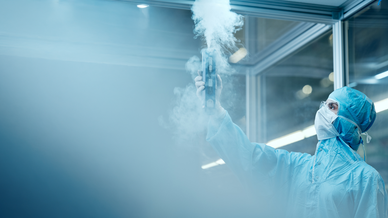 Isabella Geretschläger in Schutzkleidung, die mit einem Gerät Wasserdampf produziert.