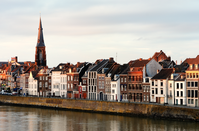 Row of charming historic buildings along a riverbank in Maastricht, the Netherlands.
