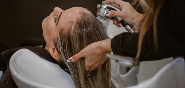 Person having their hair washed at a salon, representing healthy scalp care and ceramide-based hydration for stronger hair and improved scalp barrier function.
