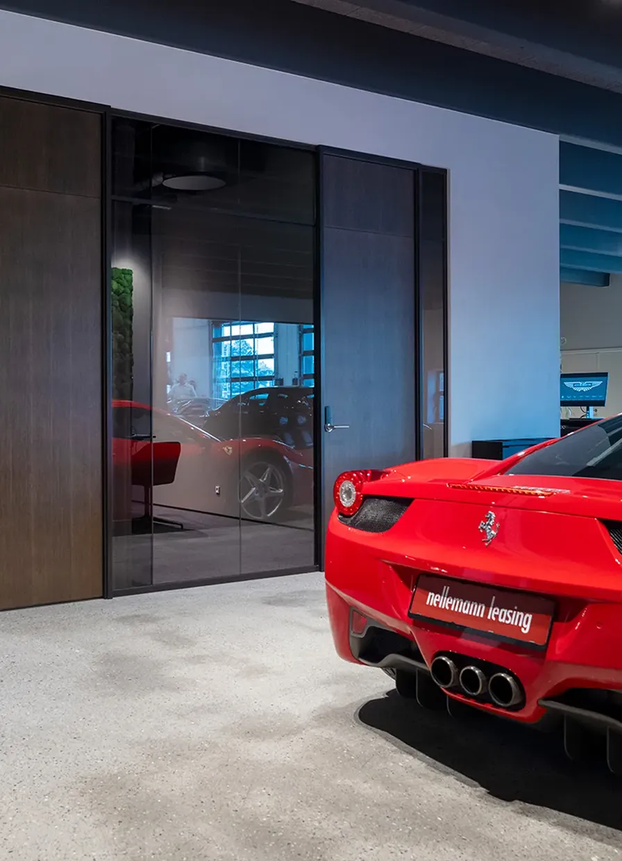 Smoked glass partitions in the Nellemann Leasing showroom, a red sports car in front