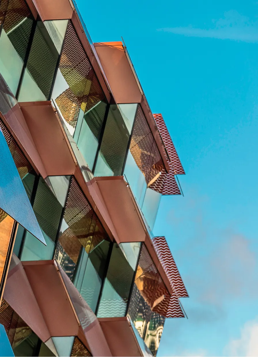 Copper and glass façade panels of Østerport II against a blue sky