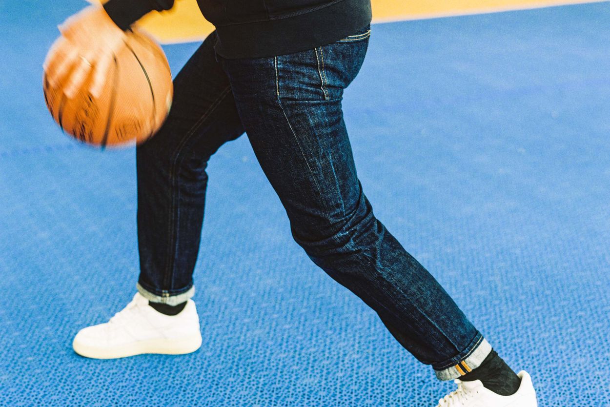 Man wearing Asket raw denim playing basketball