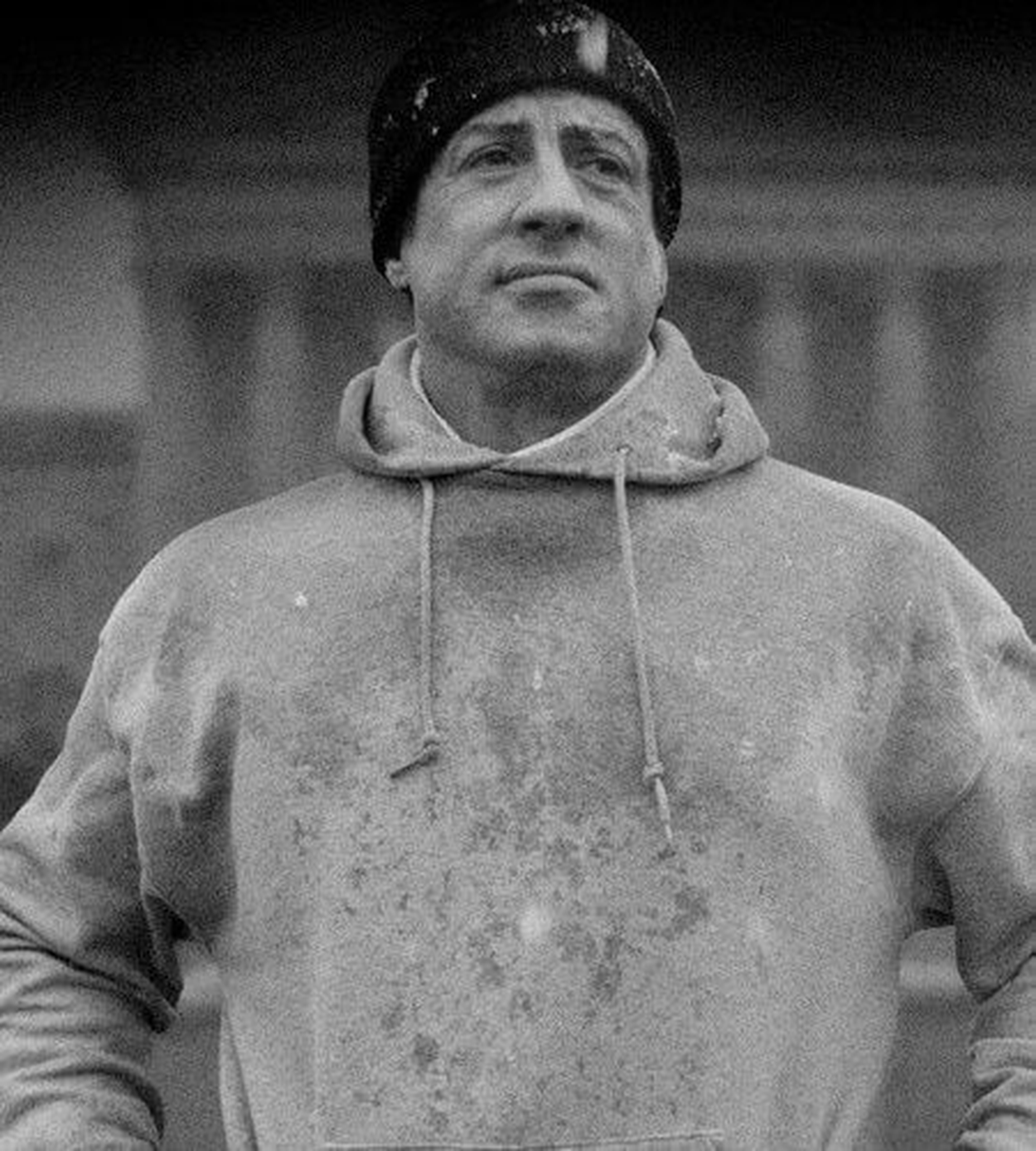 Sylvester Stallone as Rocky Balboa wearing a grey hoodie 