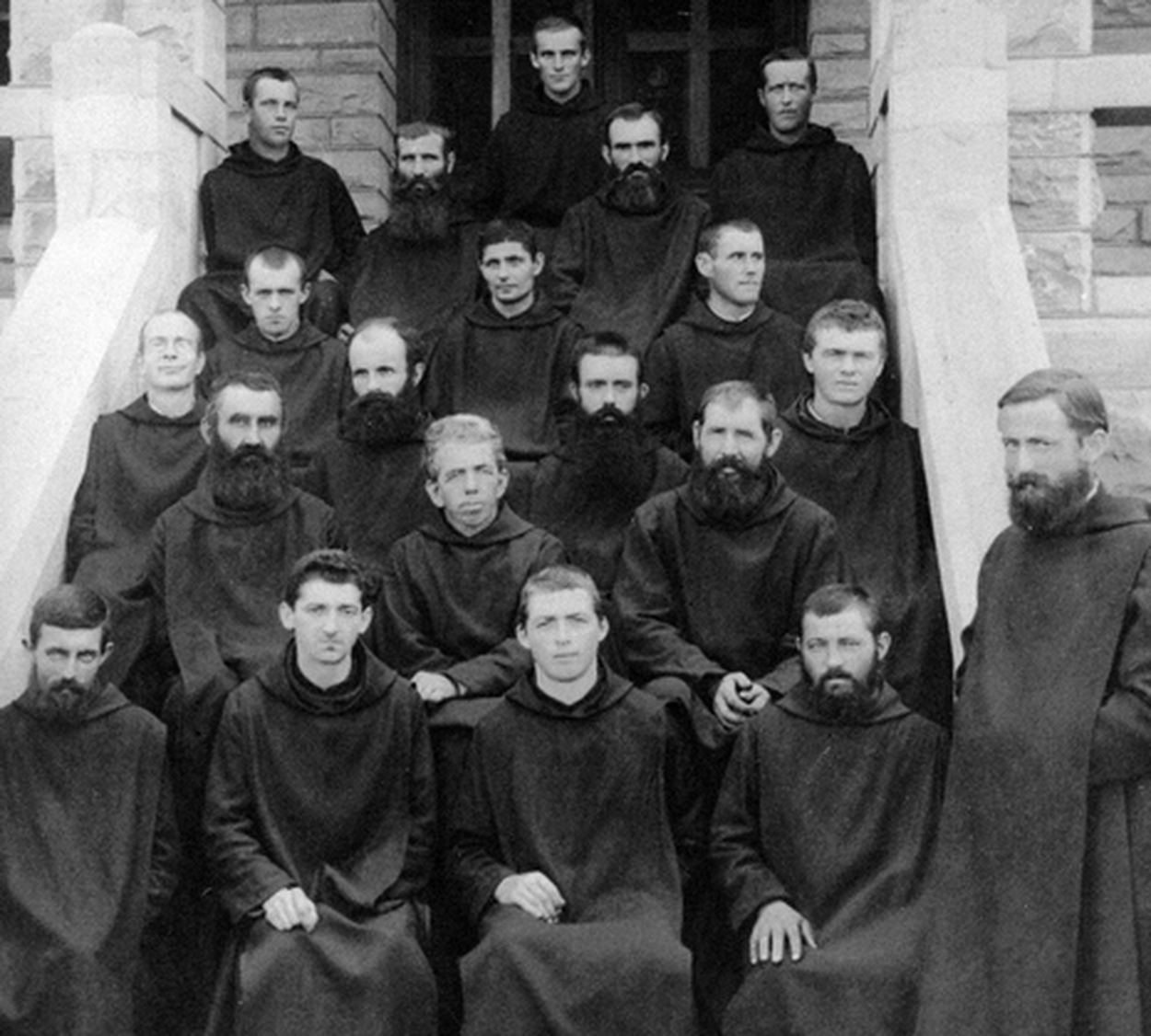 Black & white image of monks wearing hooded capes