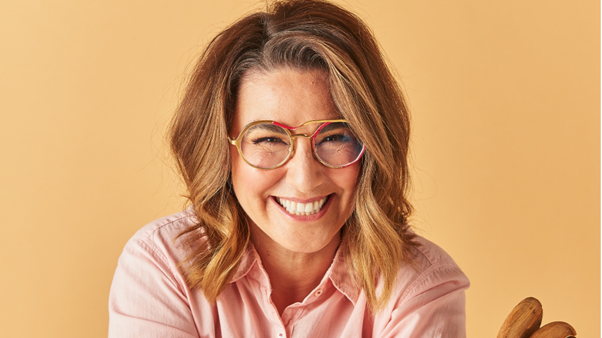 Alice smiling at the camera, in front of a light orange wall