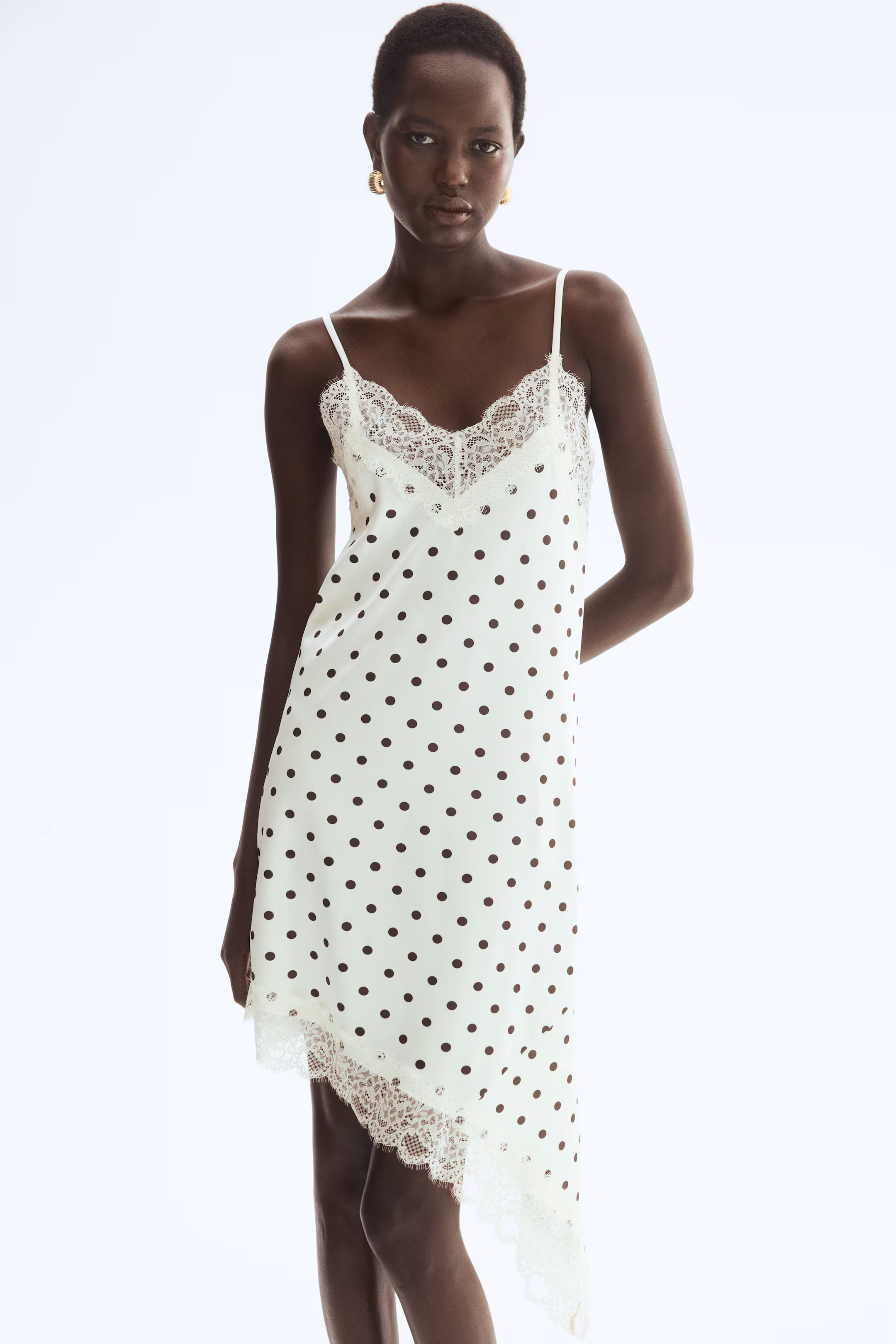 Calf length dress in jersey with lace trim at the top and hem. Features narrow shoulder straps, a V-neck and an asymmetrical hem.
