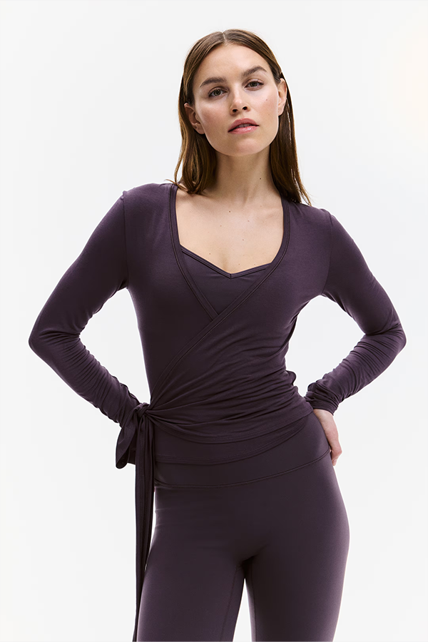 Slim fit activewear top in soft modal jersey. Features a deep, V-shaped neckline and a wrap front with ties that wrap and tie around the waist.