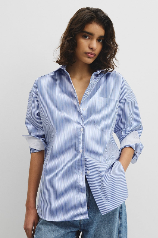 A timeless staple with a relaxed edge, the Stripe Poplin Shirt is cut from crisp cotton with a cool hand feel. Designed in an oversized silhouette, it features a curved side seam hem with a high-low finish for easy movement and layering. Finished with a centre front button placket and branded shell buttons, this everyday shirt is updated in a classic stripe pattern.