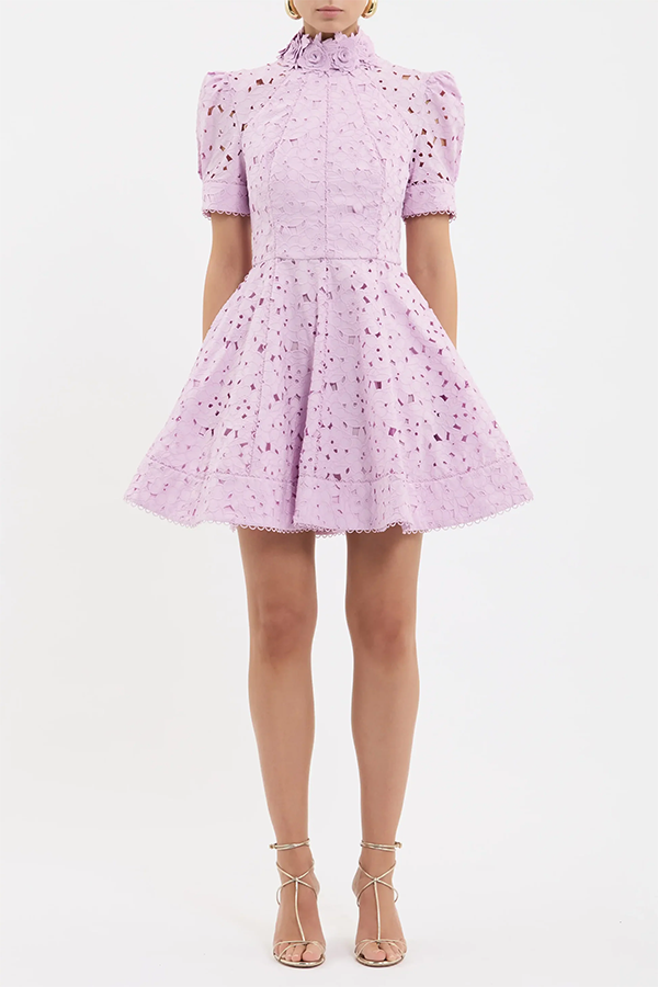 The Kitsu Mini Dress embodies feminine elegance in a soft lilac hue, tailored from broderie anglaise. Designed with a shirt dress silhouette, its high neckline, short sleeves, and fitted bodice create a sophisticated silhouette, elevated by floral and scalloped trim detailing. Cinched at the waist, the circular mini skirt includes side seam pockets for added functionality, while an invisible zip fastening at the back ensures a seamless fit. Complete with lining, this versatile dress is a wardrobe essential for elevated dressing.