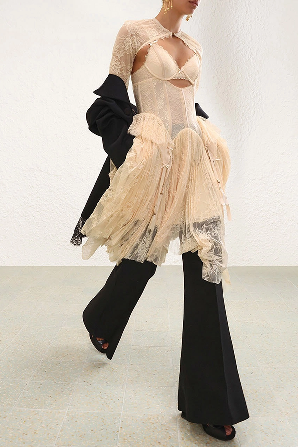The Valiant Lingerie Mini Dress in Cream from our Fall 2026 Collection, Trailblazer. A lace mini dress featuring a fitted corset bodice with structured paneling, diamond cut-out at the bust, finished with a heavily pleated sunray skirt and multi-spliced lace throughout.