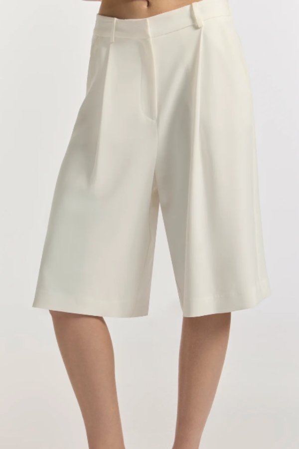 The Monologue Short in ivory. A bermuda silhouette cut with a relaxed straight leg, structural front tucks, belt loops, and pockets. An uncompromising, tailored foundation for the modern uniform.
