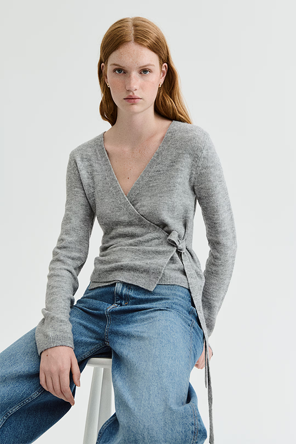 Short, fitted cardigan in a soft knit. Features a V-shaped neckline and a wrap front with wide ties on one side. Long sleeves and ribbing at the cuffs and hem.