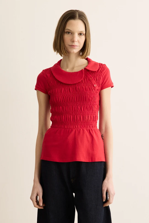 The Ferdinand Polo Top delivers a cotton piqué polo top balancing femininity with preppy style. It features a curved collar, flattering shirring across the body, an asymmetrical button placket, and short cap sleeves.