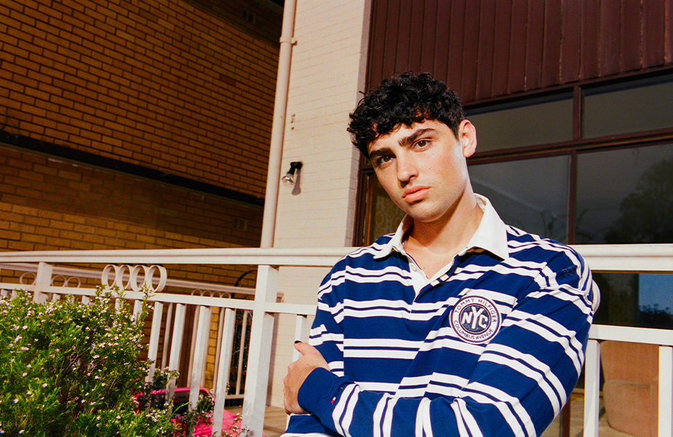 Oliver Cronin stands in front of an iron railed porch and light brick house