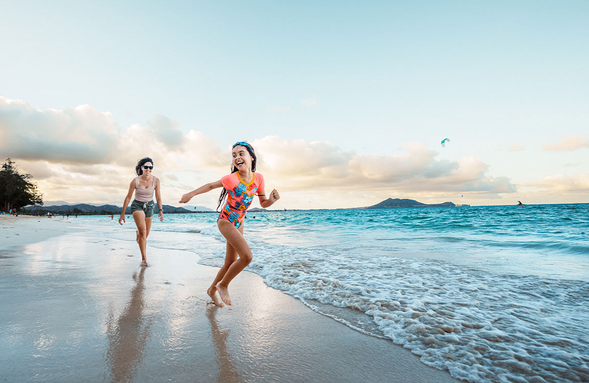 Mutter und Tochter genießen ihren Urlaub und spielen fröhlich miteinander am Strand.