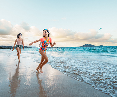 Mutter und Tochter genießen ihren Urlaub und spielen fröhlich miteinander am Strand.