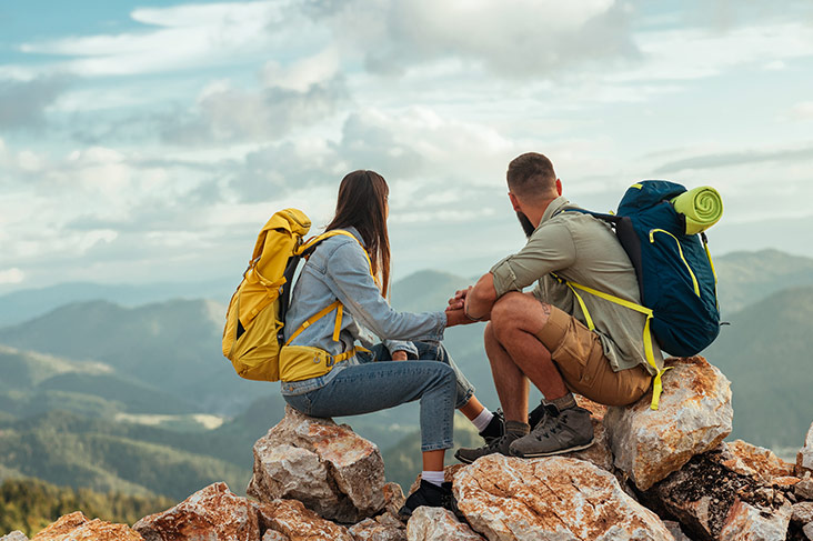 Junges Backpacker-Paar auf Wandertour genießt die Aussicht vom Gipfel