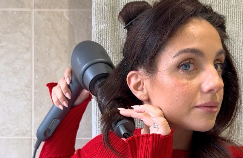 Lady wearing red curling her hair.