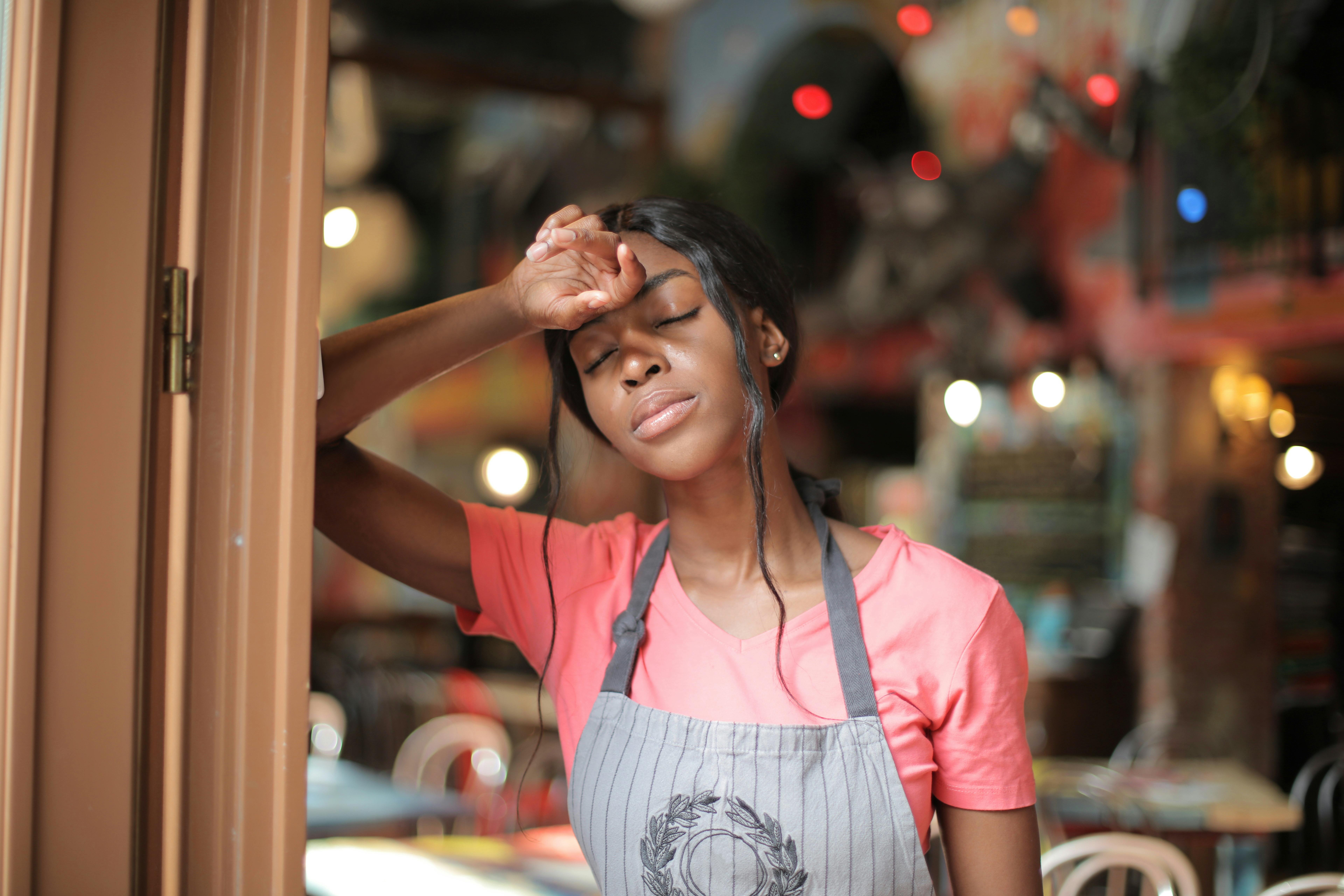 Restaurant worker in an apron looking fatigued at the end of a long shift