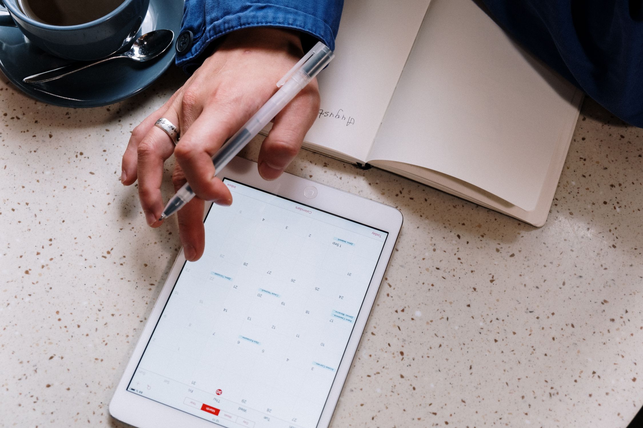 A manager reviews staff scheduling on a tablet in a busy workplace setting