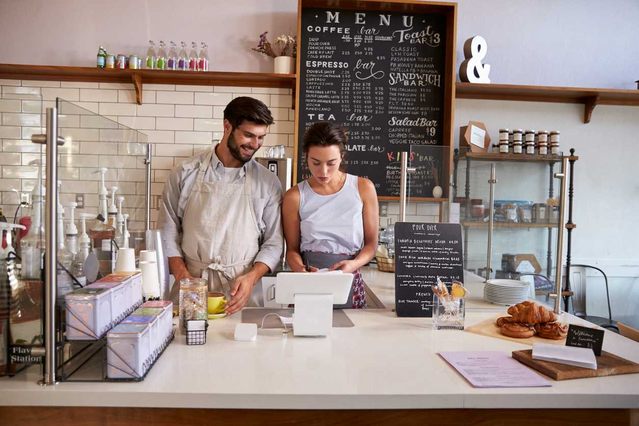 manager and employee working behind cafe counter reviewing info