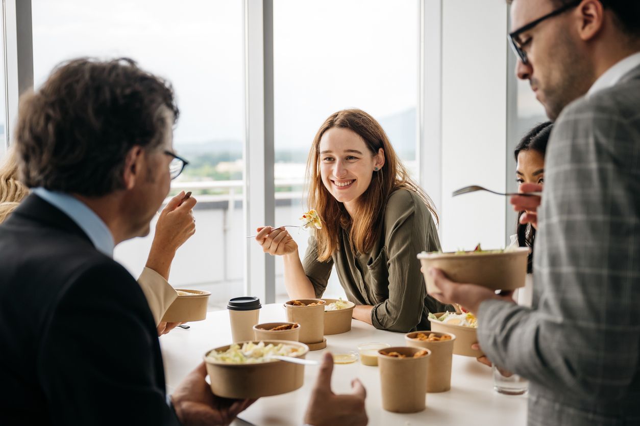 Smiling woman enjoying takeaway lunch at work stock photo
