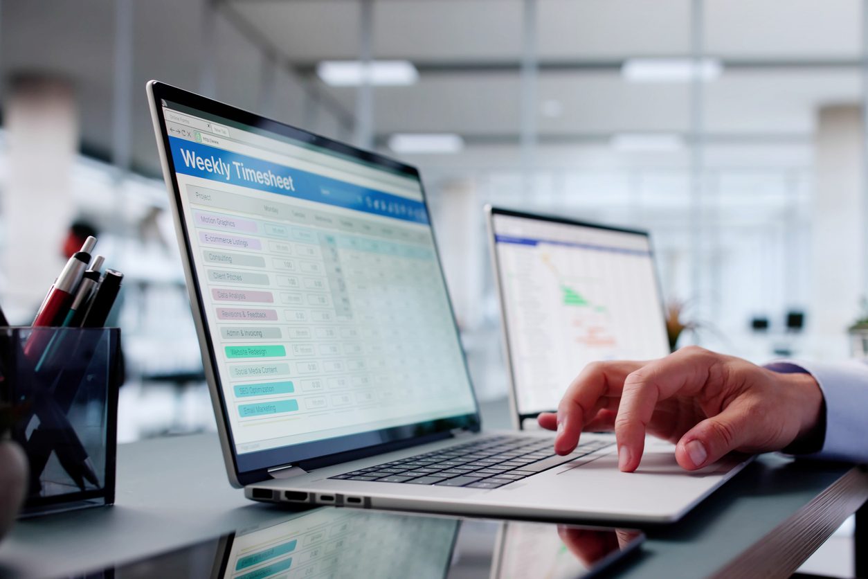 person using laptop with weekly timesheet document on screen
