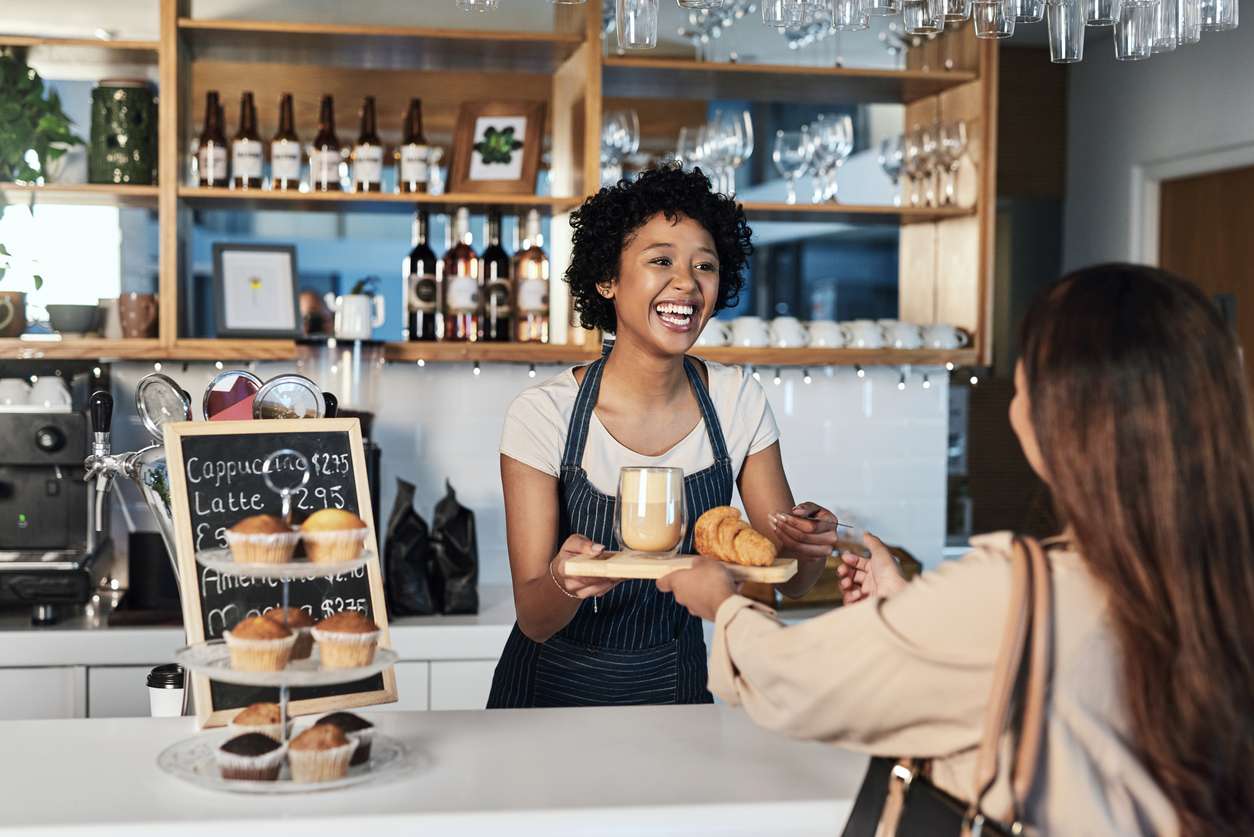 Barista in cafe serving customers and smiling