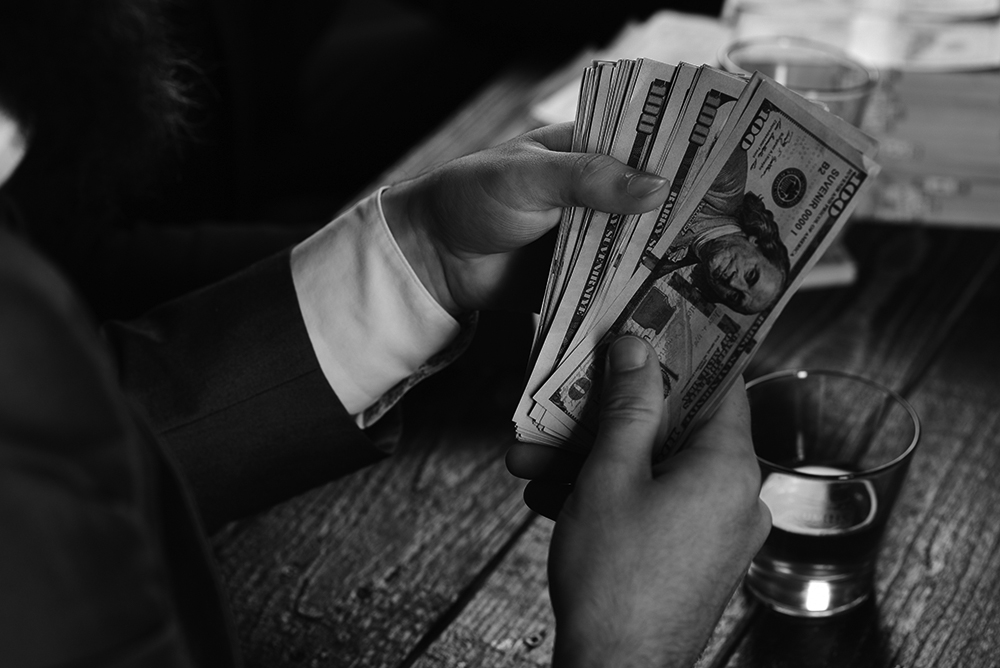 A businessman holding a fanned stack of $100 bills.