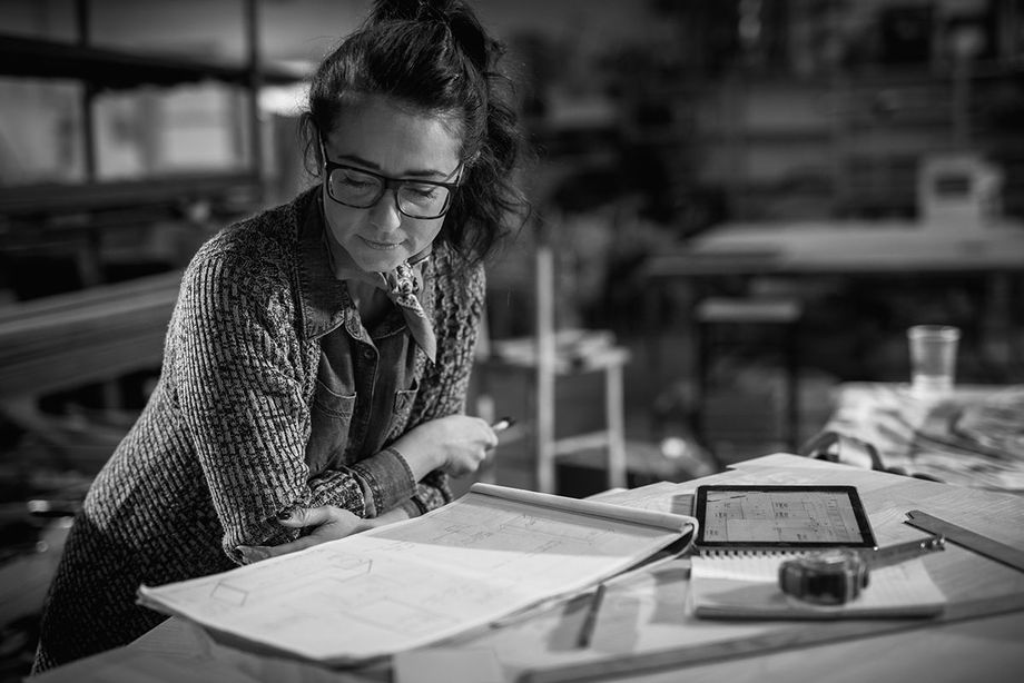 Business woman looking at blueprints in glasses