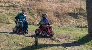 Two people riding a powerchair