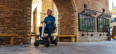 An elderly woman sitting on a mobility scooter at a table with her friends