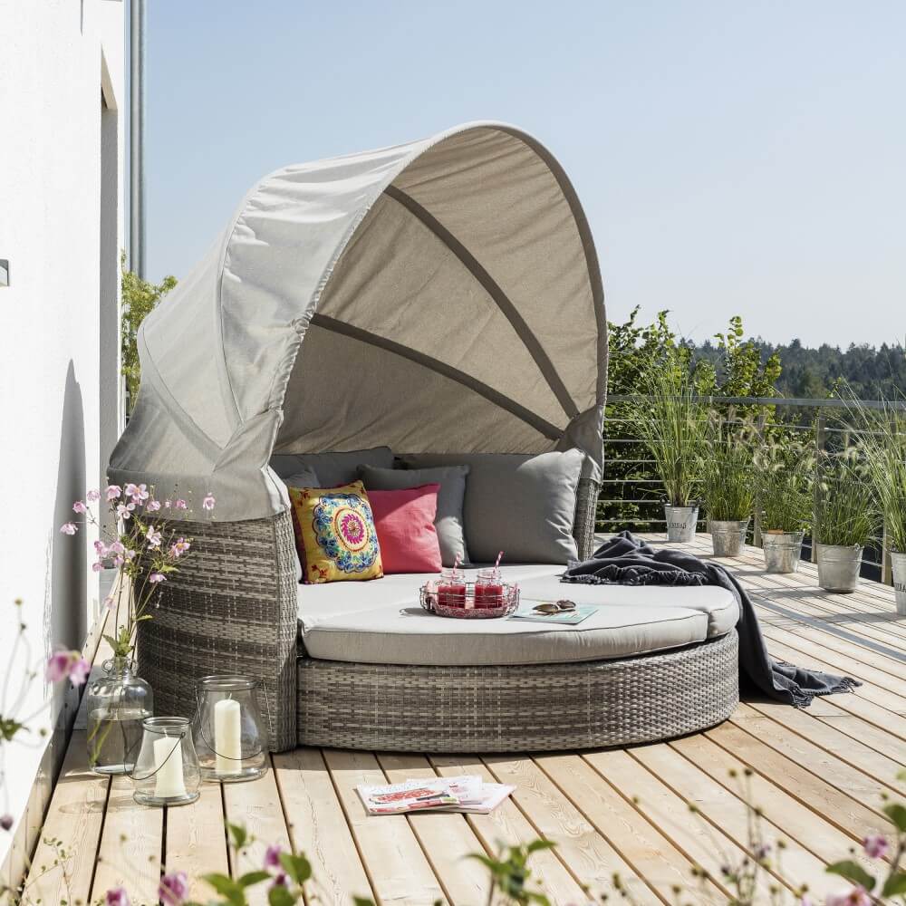 Sonneninsel mit einer runden Sitz oder Liegefläche, bunten Kissen und einem Tablett mit Getränken.