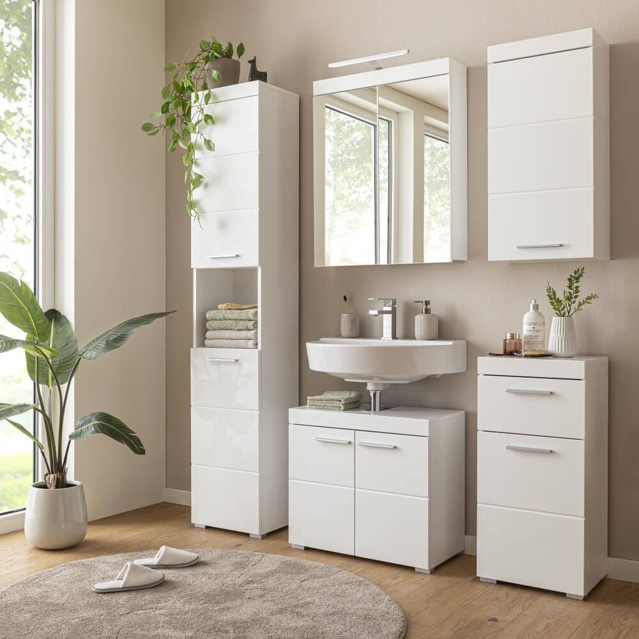 Modernes Badezimmer mit weißen Schränken, einem runden beigen Teppich, Topfpflanzen und einem Spiegel über einem Waschbecken.