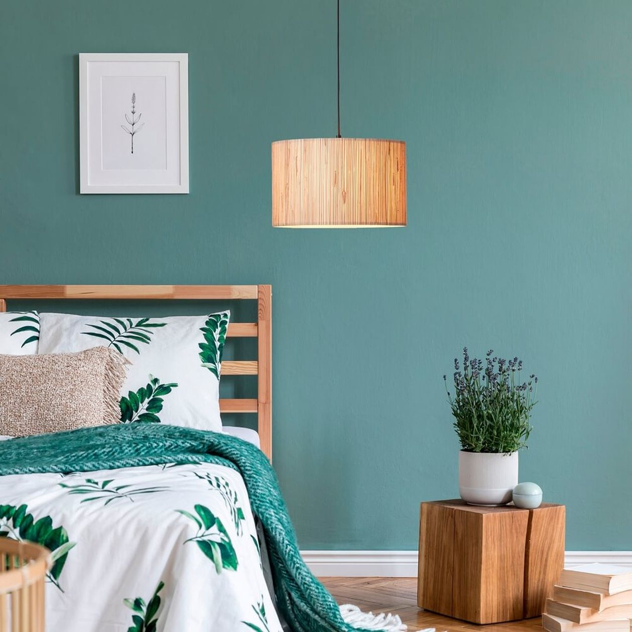 Schlafzimmer mit Holz-Pendelleuchte, Holzbett und grüner Wand, dekoriert mit Pflanzen und Naturmotiven.