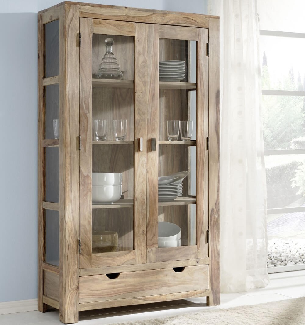 Vitrine Yoga von Wolfmöbel aus Holz. Hinter zwei großen Glastüren befindet sich Geschirr wie Teller und Gläser.