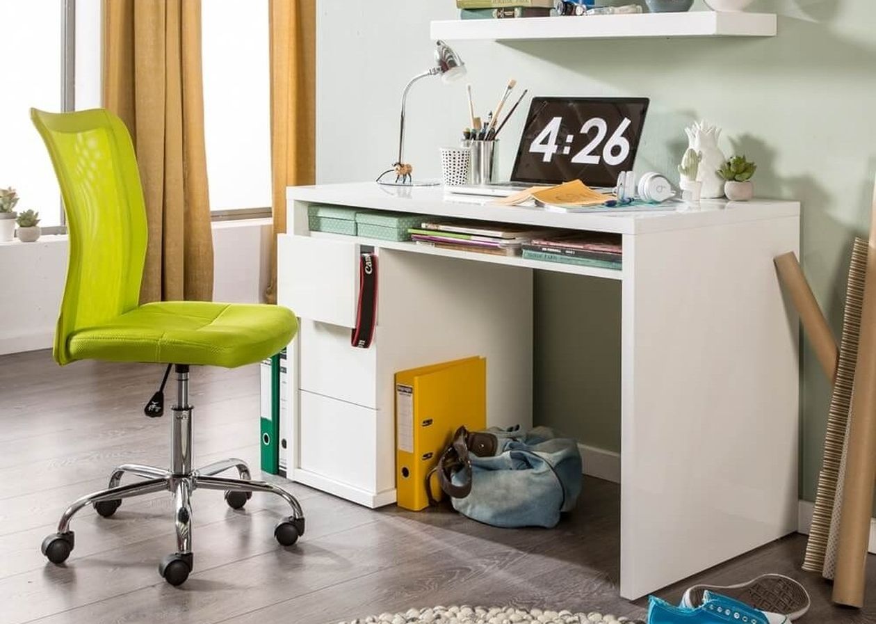 Weißer moderner Schreibtisch mit Schubladen und offenem Fach in einem Jugendzimmer mit mintgrüner Wand. Davor ein grüner Drehstuhl, darauf ein Laptop und Schreibutensilien. Hexagonale Wandregale und senfgelbe Vorhänge als Dekoration.