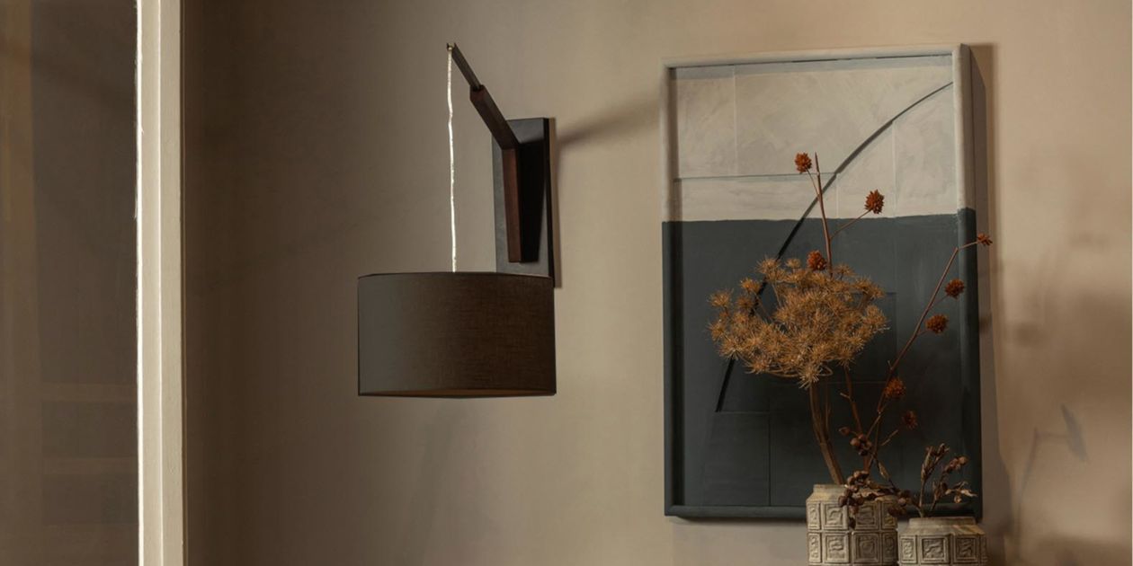 Elegante Wandleuchte wirkt als zentrales Designelement vor einem dunklen Wandpaneel. Sorgt für harmonische, moderne Lichtwirkung in hochwertigen Interior-Konzepten.