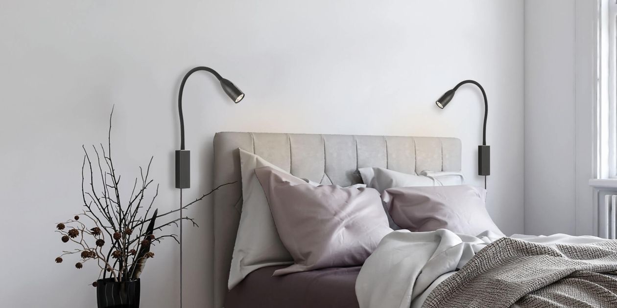 Zwei verstellbare schwarze Wandleuchten bieten flexible Lichtszenarien über einem gemütlichen Polsterbett. Ideal für stimmungsvolle Beleuchtung und komfortables Lesen im Schlafzimmer.