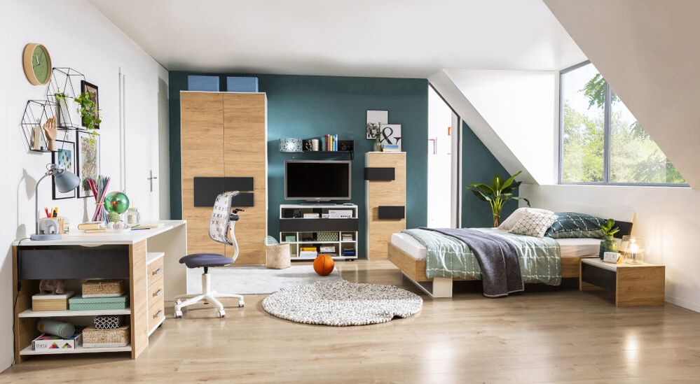 Modernes Schlafzimmer mit Holzmöbeln, Bett, Schreibtisch und Bücherregal. Heller Holzboden, türkisfarbene Akzentwand und großes Fenster mit Blick ins Grüne.