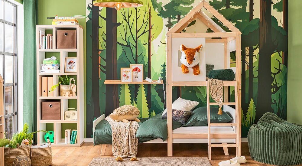 Kinderzimmer mit einer Tapete zum Thema Wald, Himmelbett, Bücherregalen, grüner Bettwäsche und einem Plüschfuchs.