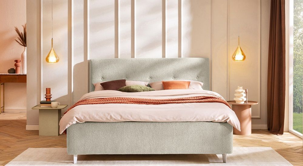 Modern bedroom with a light gray upholstered bed, pink and orange bedding, pendant lights, and side tables with decor against a paneled wall. 141 / 5.000 Modernes Schlafzimmer mit hellgrauem Polsterbett, rosa-orangefarbener Bettwäsche, braunem, orangenem und grünem Kissen, Pendelleuchten und Nachttischen mit Dekoration vor einer holzgetäfelten Wand.