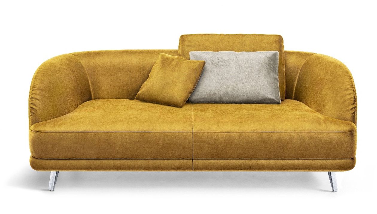 Gelbes Samtsofa mit geschwungenen Armlehnen, zwei Kissen – eines gelb, eines grau – auf schlanken Metallbeinen, vor weißem Hintergrund.