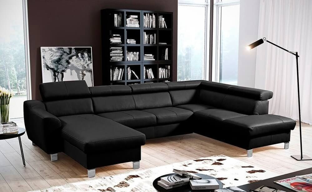Große U-förmige Wohnlandschaft aus schwarzem Leder mit verstellbaren Kopfstützen und Chromfüßen in einem Wohnzimmer mit dunklem Bücherregal und bodentiefen Fenstern.
