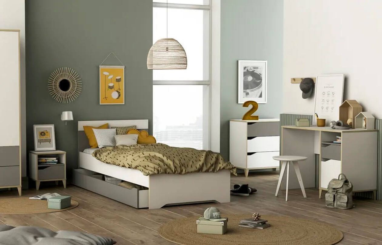 Modernes Jugendzimmer in Grau und Weiß mit Bett mit Bettkasten, Nachttisch, Kommode, Kleiderschrank und Schreibtisch. Ein Mädchen sitzt auf dem Bett und schaut auf ihr Smartphone. Die Wand ist grün mit weißen Sternen dekoriert.